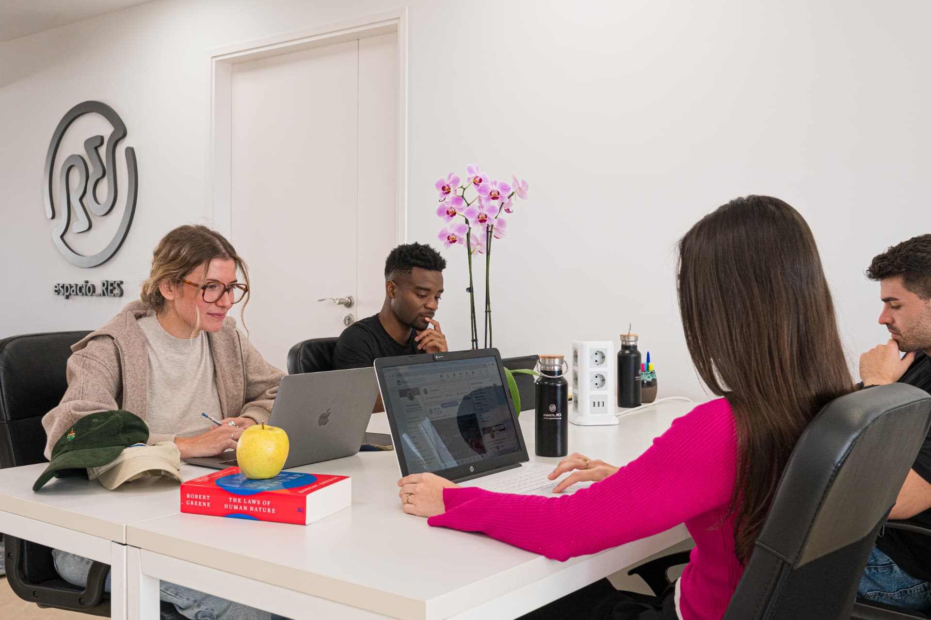 Estudiantes trabajando con portátiles en una mesa de espacio_RES